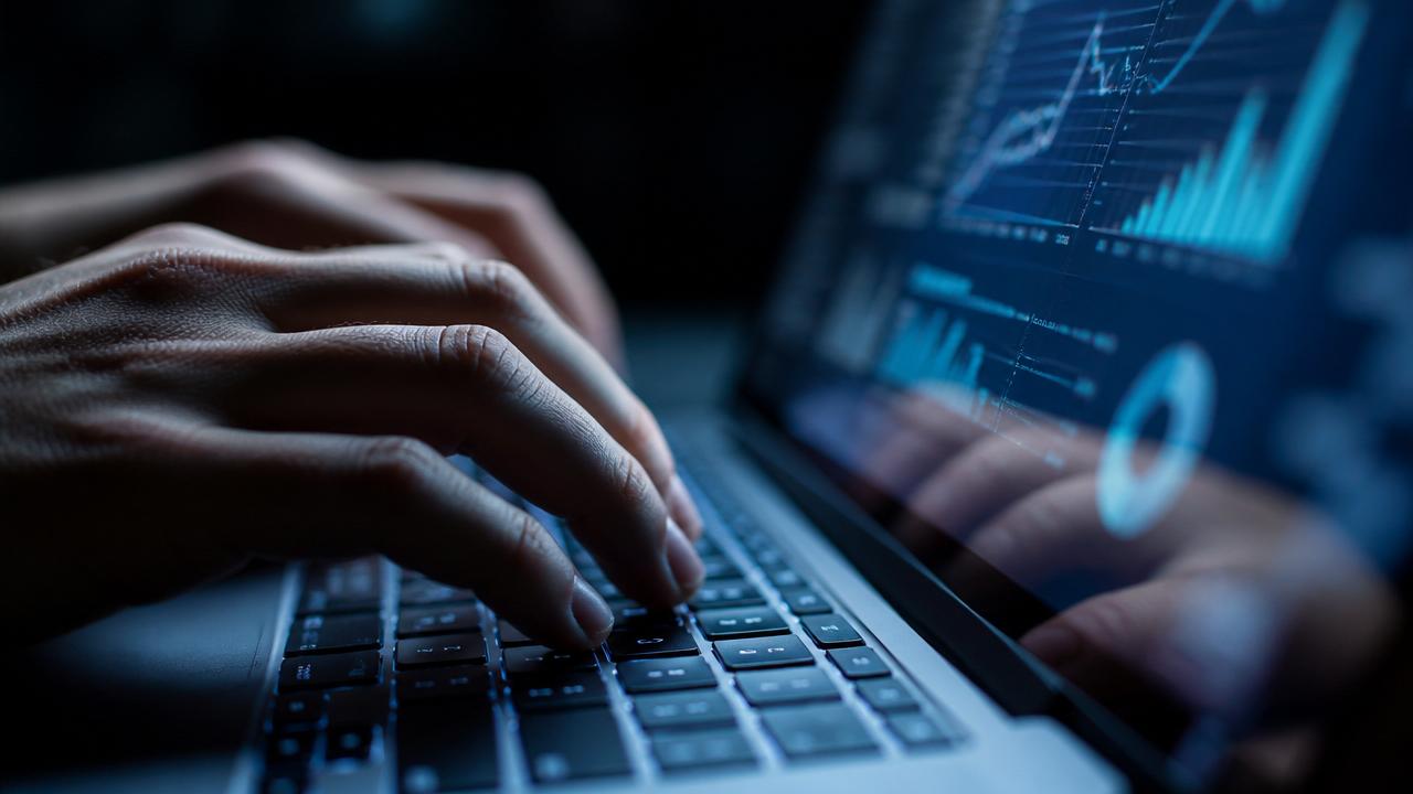 Hands typing on laptop with analytics dashboard visible on screen